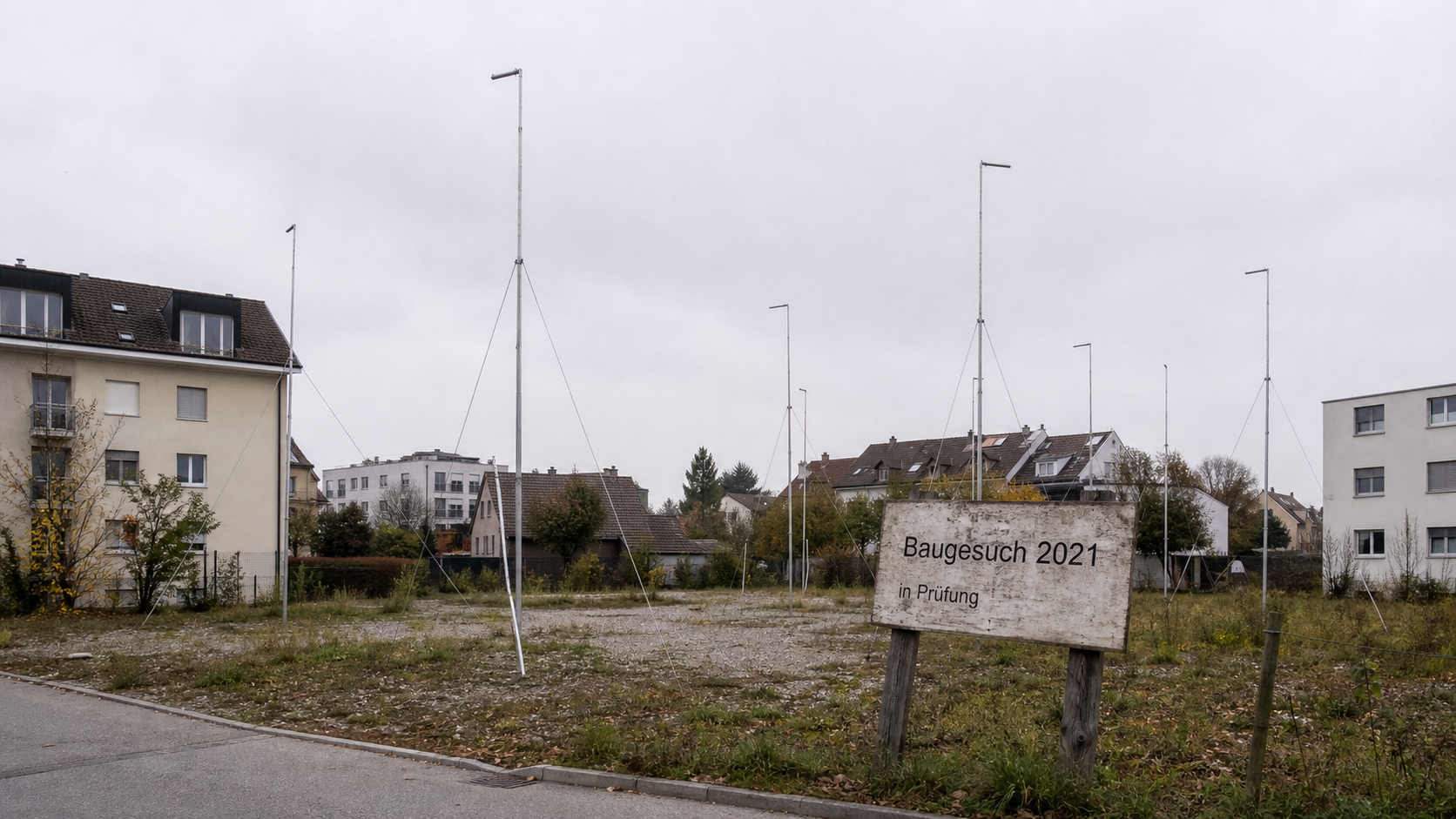 Leeres Grundstück mit Baugespann und alter Bauankündigungstafel